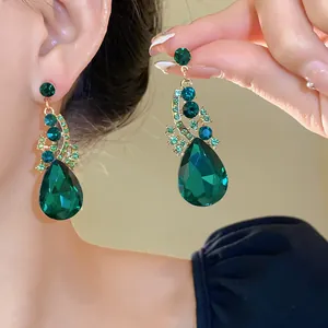 Detail view of luxurious emerald green teardrop crystal dangle earrings with gold-tone accents