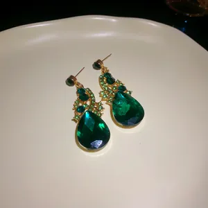 Detail shot of green waterdrop earrings with rhinestones on a white ceramic tray