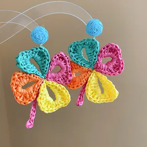 Detail of colorful handmade raffia straw woven flower earrings with silver needles.