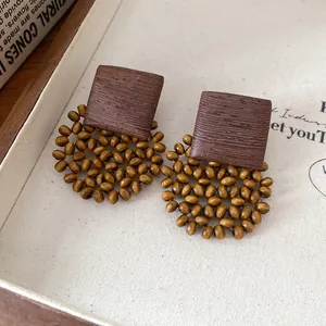 Macro view of bohemian square dark wood and yellow beaded earrings in vintage French style