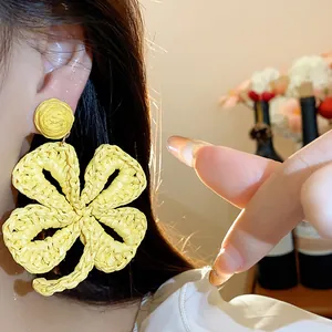 Close-up detail of yellow raffia woven flower earrings with artisanal texture