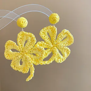 Close-up of bright yellow raffia woven flower earrings with intricate crochet texture