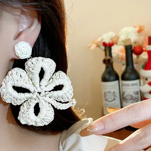 Detailed view of large white raffia woven flower earrings for a chic resort-style look.