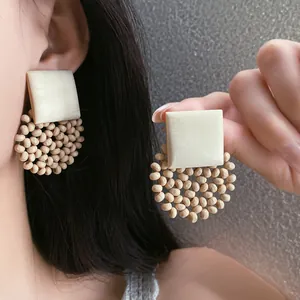 Detail of bohemian square beaded earrings showing natural wood texture and wearing effect