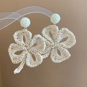 A detailed view showing the intricate texture of cream raffia woven flower earrings
