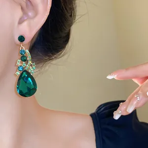 Close-up view of elegant emerald green crystal water-drop earrings worn by a model in detail.