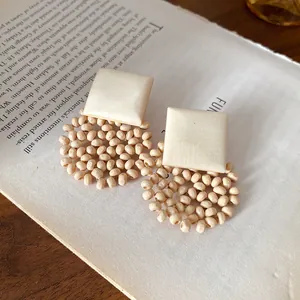 Detail shot of bohemian square stud earrings with wooden bead circular mesh design.