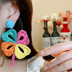 Detailed close-up of vibrant handmade woven raffia flower earrings worn by an Asian model