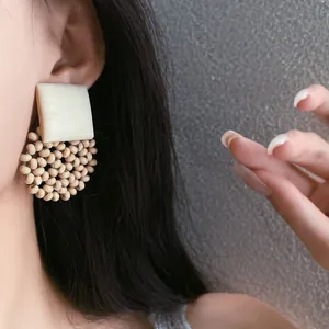 Detailed close-up of Bohemian style square and circular beaded earrings on a model