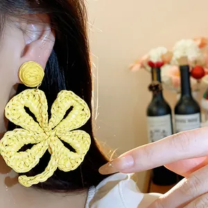 Detailed macro view of yellow handmade raffia woven flower earring for summer vacation