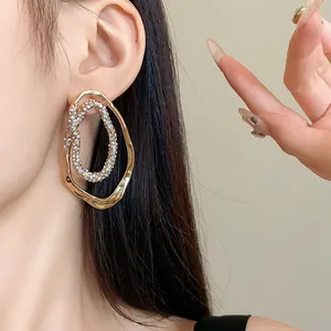 Detalle de pendientes ovalados irregulares chapados en oro con brillantes diamantes