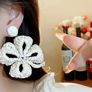 Close-up detail of white raffia woven flower earring worn on ear for a vacation look