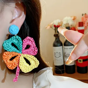 Close-up of colorful raffia woven flower earring on ear for bohemian vacation style