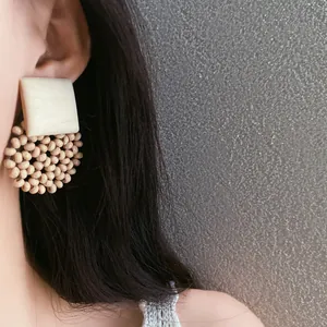Detailed macro view of bohemian square cream top and circular wood beaded earrings