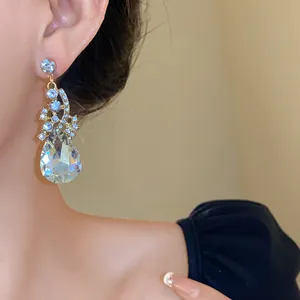 Detailed close-up view of a luxury sparkling water-drop crystal drop earring worn by a model