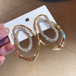 Primer plano de pendientes ovalados dorados con detalles de cristaux brillantes