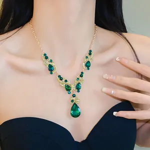 Close-up of elegant gold necklace with vibrant green teardrop rhinestones on model