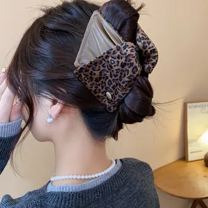 Detailed view of a leopard print triangular hair claw clip used to secure a bun hairstyle
