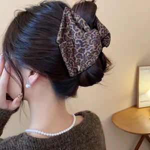 Macro view of a large acrylic leopard print bow hair claw clip for elegant updo hairstyles