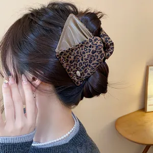 Close-up of a large leopard print triangular hair claw clip worn in a messy bun.
