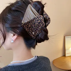 Detailed view of a large leopard print triangular hair claw clip on dark brown hair