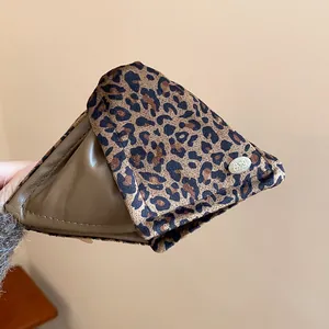 Close-up of a large triangular hair claw clip with leopard print and olive green acrylic.