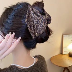 Close-up of a large leopard print triangular hair claw clip styled on a high hair bun