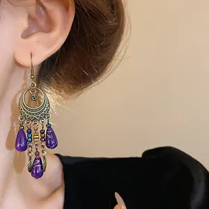 Dettaglio ravvicinato di orecchini etnici a goccia con perle di vetro viola in stile vintage