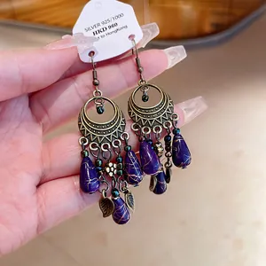 Primo piano di orecchini vintage in bronzo con perline viola a goccia e ciondoli a foglia