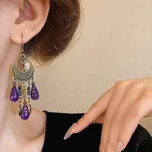 Primo piano di orecchini pendenti etnici vintage con perline viola a goccia d'acqua