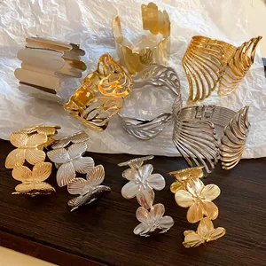 Close-up view of gold and silver metal cuff bracelets with leaf and butterfly designs