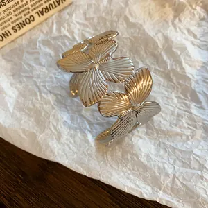 Detailed view of an elegant silver butterfly leaf cuff bracelet on a white paper background
