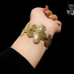 Close-up of a gold-finished metal cuff bracelet featuring large textured flowers