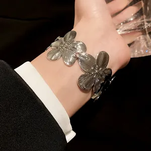 Elegant silver metal flower cuff bracelet featuring textured petals shown on a model wrist