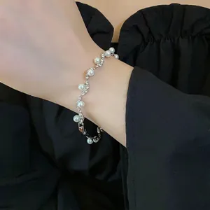 Elegant irregular wavy bracelet featuring white pearls and sparkling rhinestones on silver metal.
