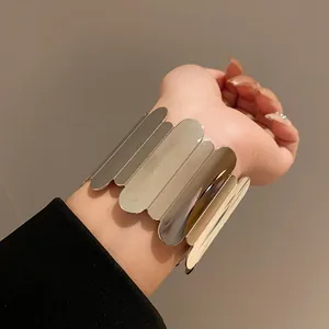 Close-up of a stylish wide silver metallic leaf-shaped cuff bracelet worn on the wrist