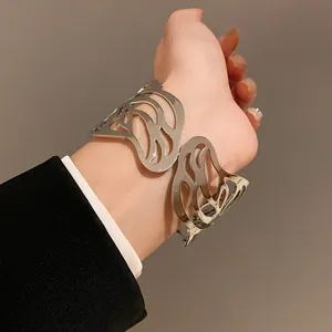 Close-up view of a silver-toned metal leaf cutout cuff bracelet worn on a wrist