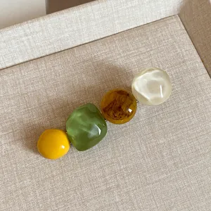 Detailed close-up of colorful resin beads on a minimalist geometric metal hair clip