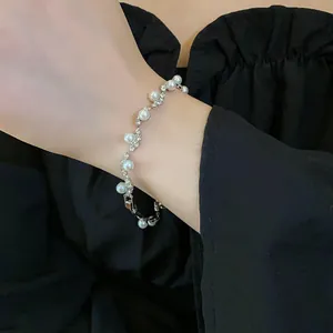 Close-up detail of a vintage irregular pearl bracelet with sparkling rhinestones on a wrist