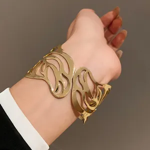 Close-up of a stylish gold-toned wide open cuff bracelet featuring an intricate leaf cutout design