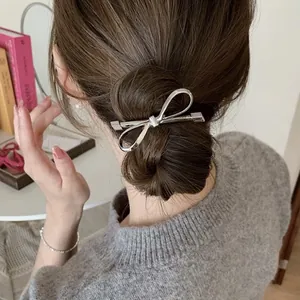 Detailed view of a silver bow hair clip on a brunette bun for a Korean aesthetic style