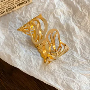 Close-up of golden metallic leaf cutout cuff bracelet on textured background