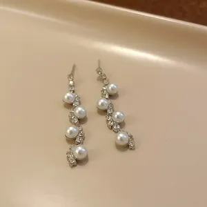 Elegant long drop earrings with wavy rhinestone patterns and five white pearls