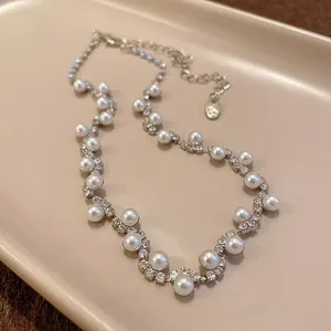 Close-up of an elegant irregular pearl bracelet with sparkling rhinestones on a beige tray.