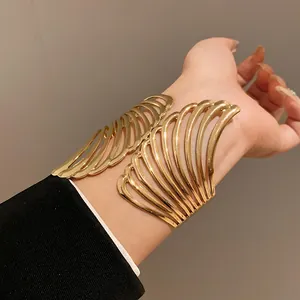 Detailed close-up of an elegant gold wing-shaped cuff bracelet worn on a woman's wrist