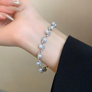 Detailed view of elegant silver wave bracelet featuring white pearls and sparkling rhinestones