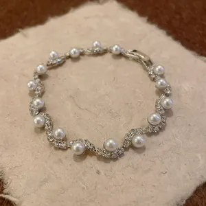 Detailed view of a vintage silver wavy bracelet with pearls and sparkling rhinestones