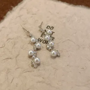 Detailed macro view of irregular wavy earrings with white pearls and sparkling rhinestones
