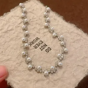 Macro view of irregular silver bracelet with pearls and rhinestones on textured paper