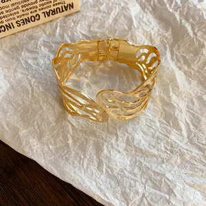 Detailed view of a gold-plated metal cuff bracelet with aesthetic hollow leaf patterns.